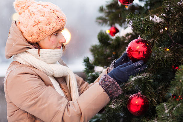 istock happy young woman decorating christmas tree 174943892
