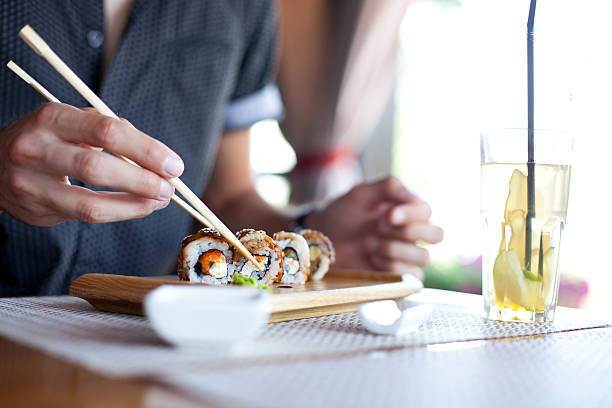 homens jovens comendo sushi - sushi chopsticks sushi bar food - fotografias e filmes do acervo