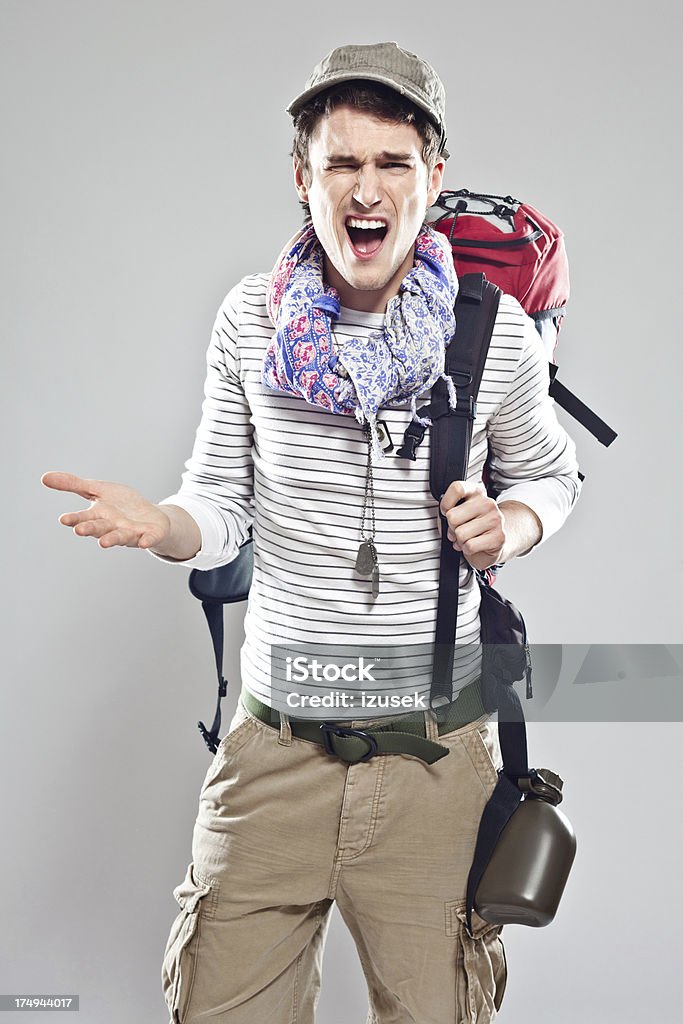Irritated tourist Portrait of furious and complaining young backpacker. Studio shot, grey background. Hiking Stock Photo