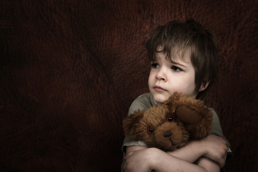 Child abuse theme - scared child with teddy bear