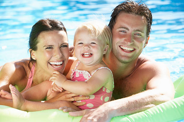istock A family smiling while on a Lilo in a swimming pool 174944748