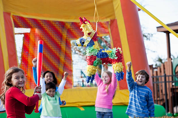 Pinata at children's birthday party Multi-ethnic children (7-10 years) having fun at birthday party. Focus on pinata and girl holding stick. birthday party bounce house stock pictures, royalty-free photos & images