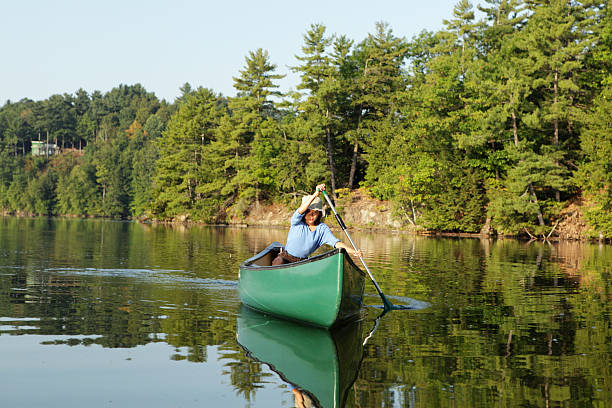 istock Outdoors girl paddling canoe on lake 174946562