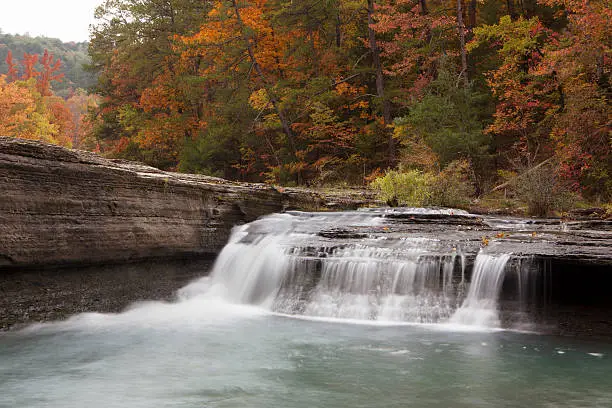 "Peak fall colors at the Haw Creek waterfall in Pelsor, Arkansas"
