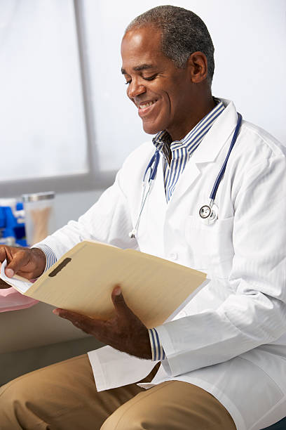 istock Male Doctor In Surgery Reading Patient Notes 174948382