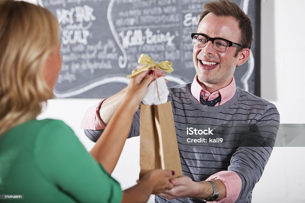 Customer making purchase at beauty salon Woman making purchase at beauty salon.  Focus on man behind counter (30s). 30-39 Years Stock Photo