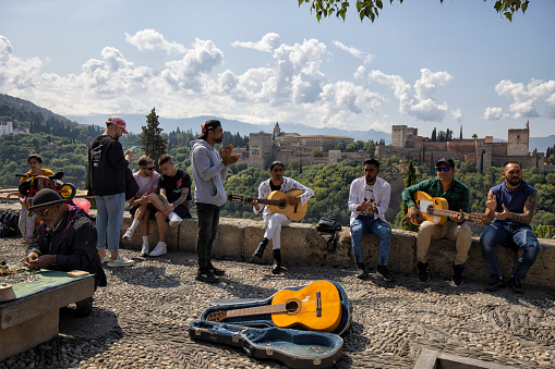 Mirador De San Nicolás at the top of Albaicín district in Granada, Spain. A small group of music performer entertaining tourists with guitars.