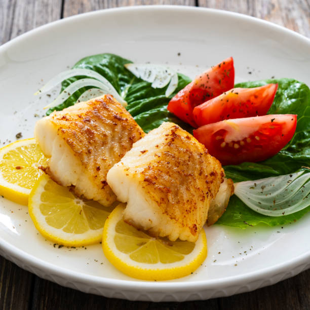 istock Fried cod fillet and fresh vegetables on wooden table 1749495605