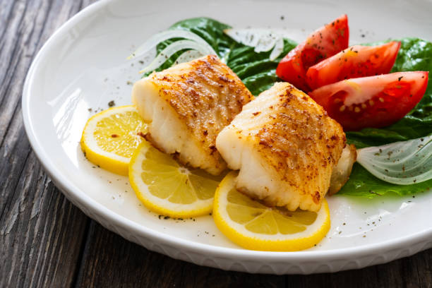 istock Fried cod fillet and fresh vegetables on wooden table 1749495624