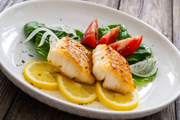 istock Fried cod fillet and fresh vegetables on wooden table 1749495638