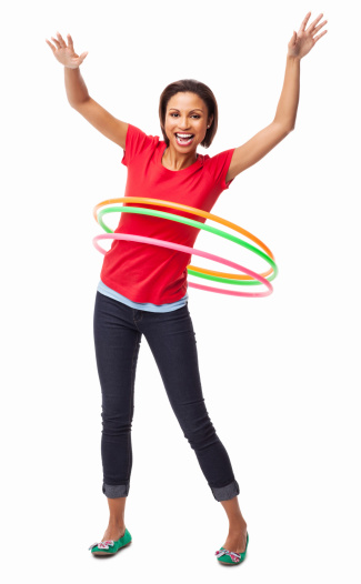 Full length portrait of an exhilarated African American woman in casual wear playing with hula hoop. Vertical shot. Isolated on white.