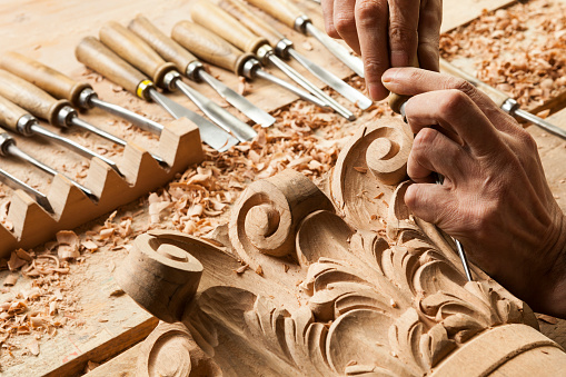 Woodworker carving a wood decorative object,