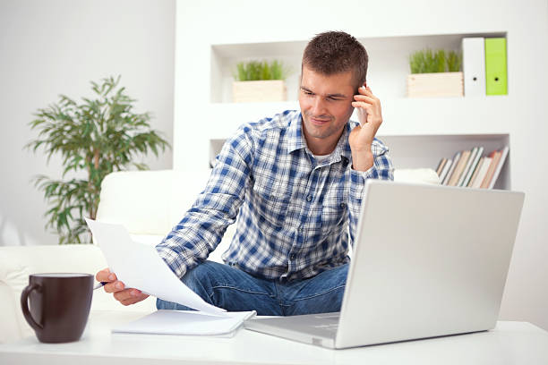 istock Man on phone with a laptop, looking at a paper 174951909