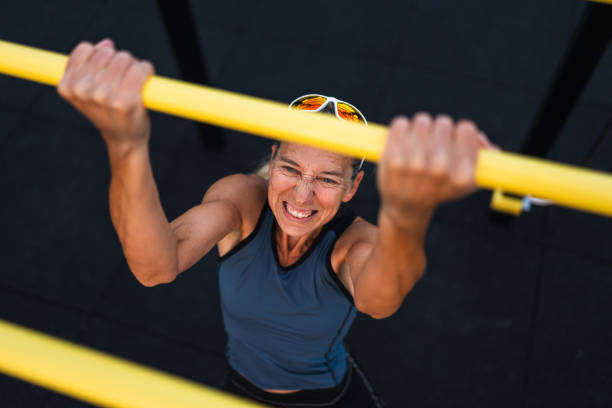 athletic mature adult woman exercising strenuous pull ups