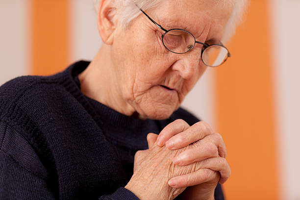 istock elderly woman praying 174952701