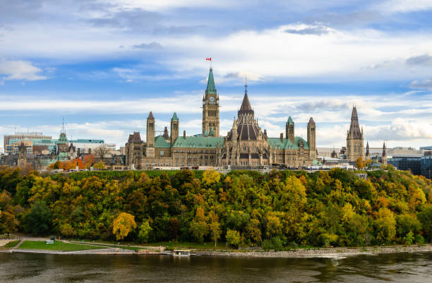 Autumn view of Parliament Hill and Ottawa River in Ottawa, Canada Stunning autumn view of Parliament Hill across the Ottawa River in Ottawa, Canada canada flag blue sky clouds stock pictures, royalty-free photos & images
