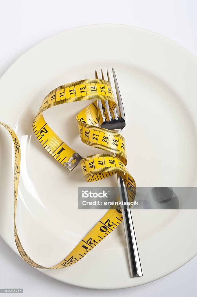 Fork with measuring tape Fork with measuring tape on white plate. Healthy eating.Some similar photographs from my portfolio:For similar images Balance Stock Photo