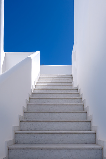 View of a whitewashed buildings steps leading upstairs and a blue sky in Ios Greece
