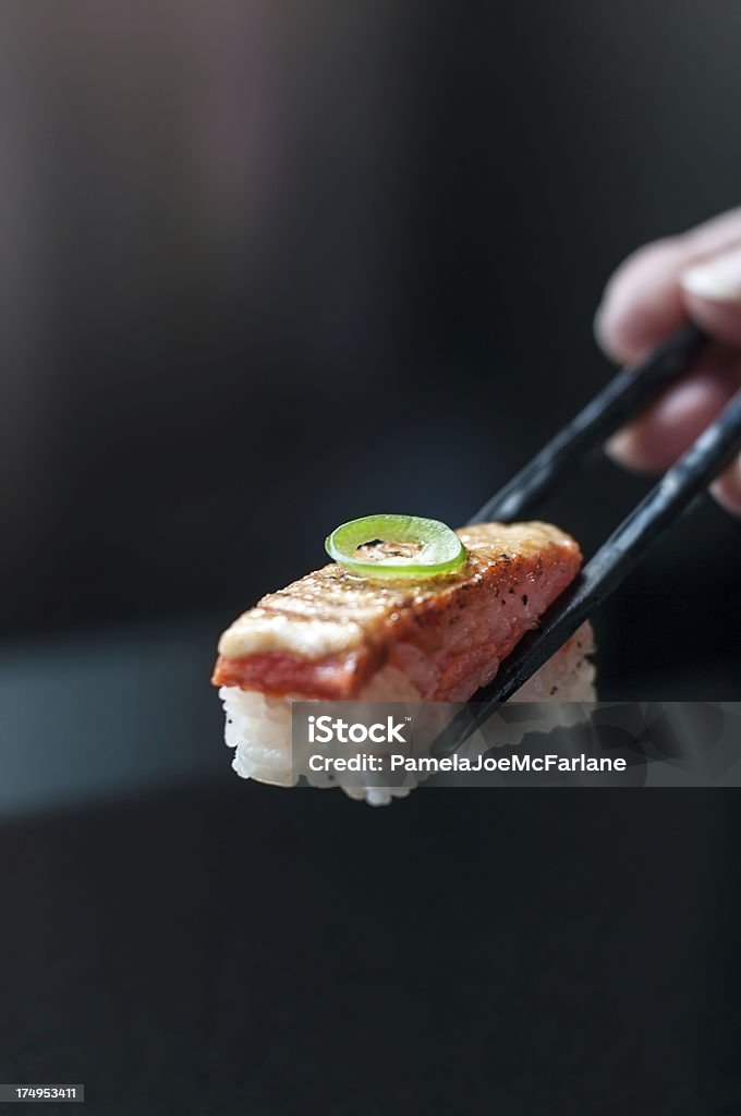 Sushi di salmone possesso di Bacchette cinesi - Foto stock royalty-free di Sushi