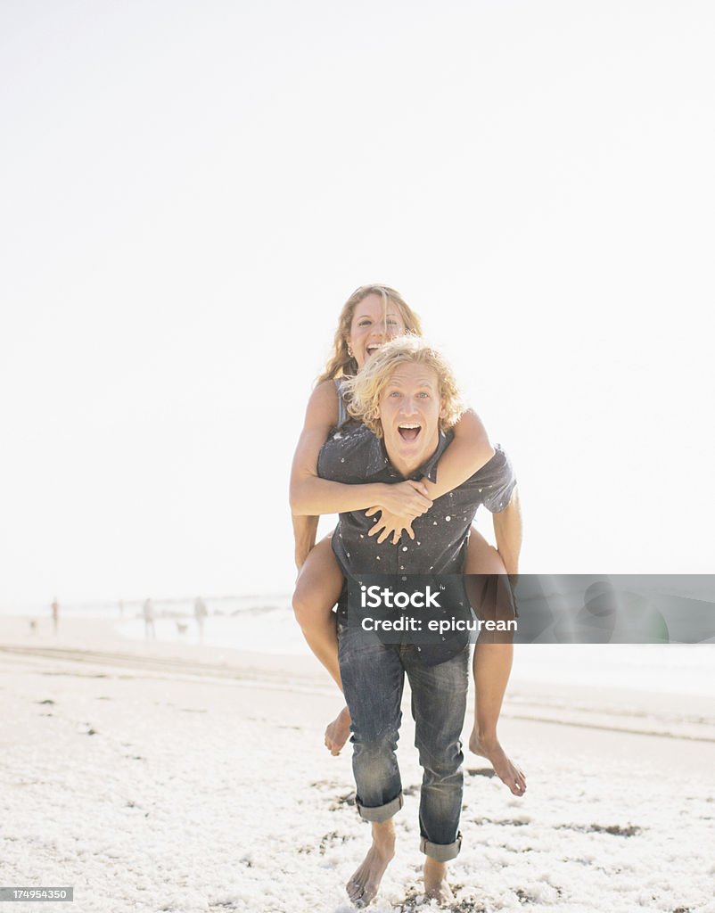 Bas de bikini surfeur garçon donnant à sa copine un piggy back ride - Photo de Adulte libre de droits