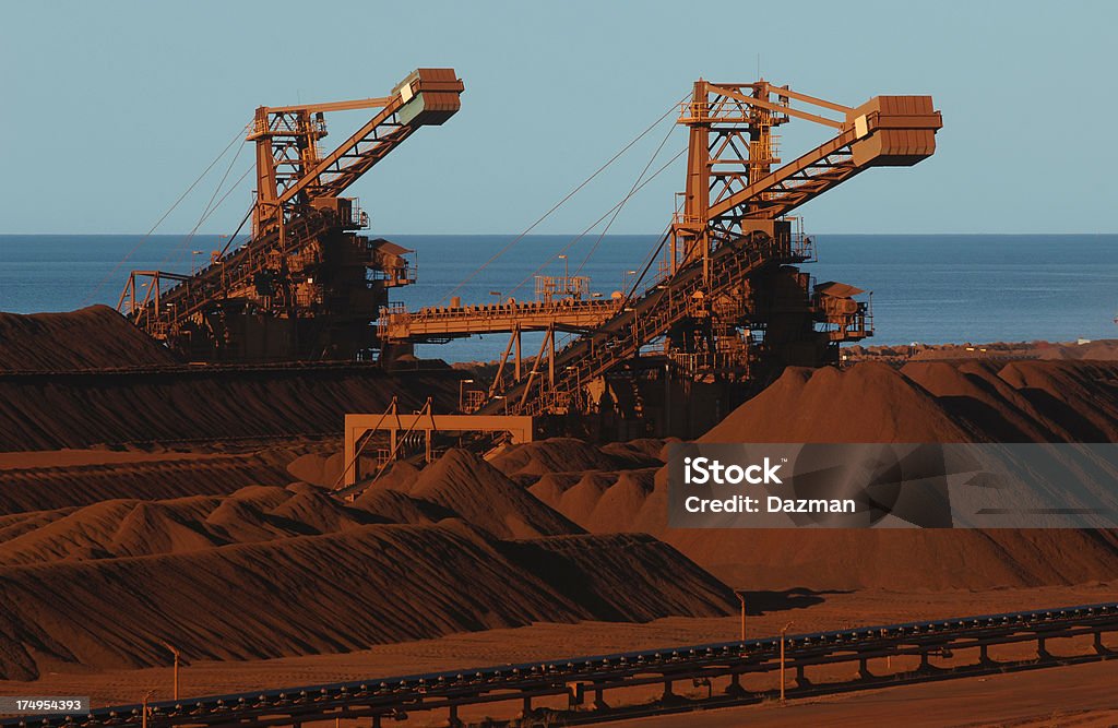 Two iron ore stackers working in a stockyard. An elevated view of two ore stackers used to stockpile crushed iron ore on a mine site. Iron Ore Stock Photo