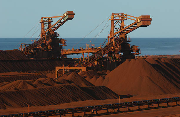 Two iron ore stackers working in a stockyard. An elevated view of two ore stackers used to stockpile crushed iron ore on a mine site. Reclaimer stock pictures, royalty-free photos & images