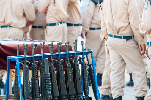 A rack of guns and a table of Hebrew Bibles, or Tanach, are ready for the start of an air force cadet graduation ceremony at the Western Wall. Cadets in the background.