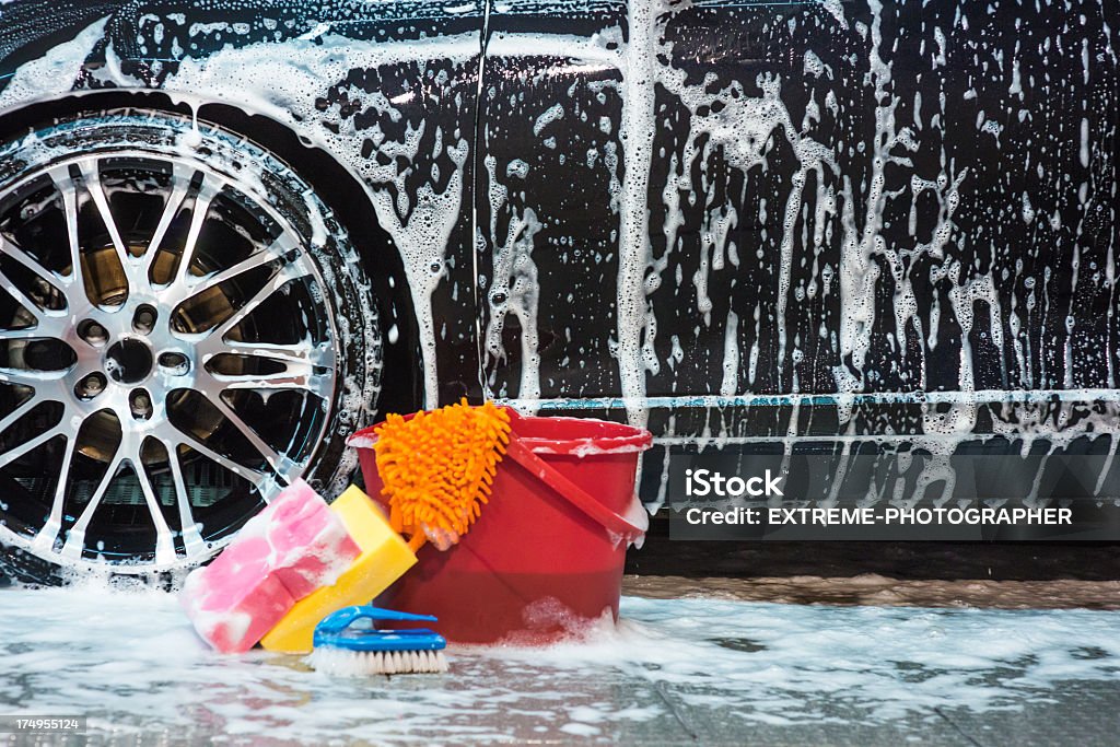 Cleaners and cleansers Bucket with sponges and brush with lots of foam next to car tire. Car Stock Photo