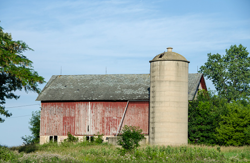 Old concrete stave silo of poured cement standing next to an abandoned  barn. Near Calamus, Wisconsin, USA.