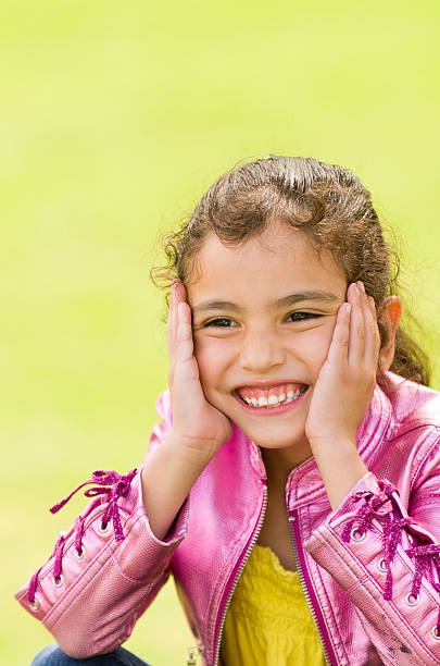 Smiling Little Girl with Hands on Face stock photo