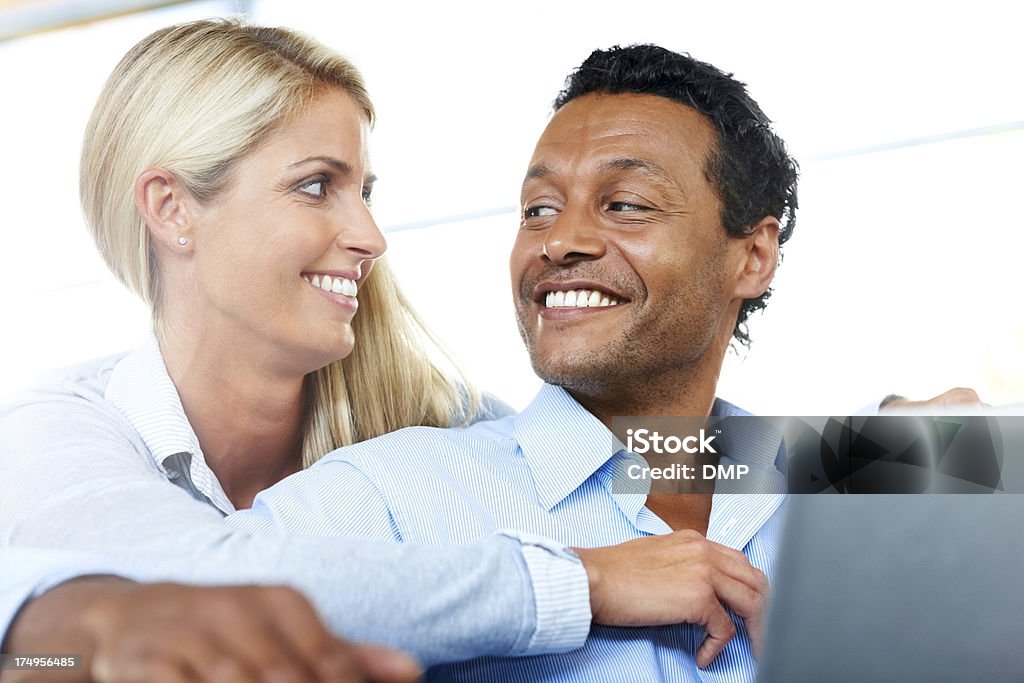 Beautiful couple smiling with laptop Portrait of smiling couple looking at each other with a laptop Blond Hair Stock Photo