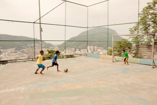 Three young Brazilian boys from the favelas play a game of pick up soccer.