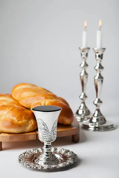 Wine, challah and candles for the Jewish Sabbath. Selective focus on the wine.