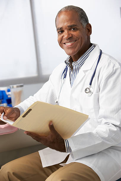 istock Male Doctor In Surgery Reading Patient Notes 174957584