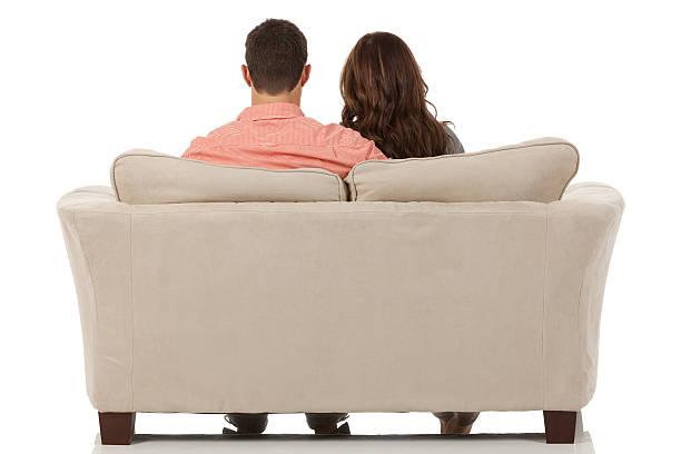 Rear view of couple sitting on a couch Rear view of couple sitting on a couchhttp://www.twodozendesign.info/i/1.png couch back stock pictures, royalty-free photos & images