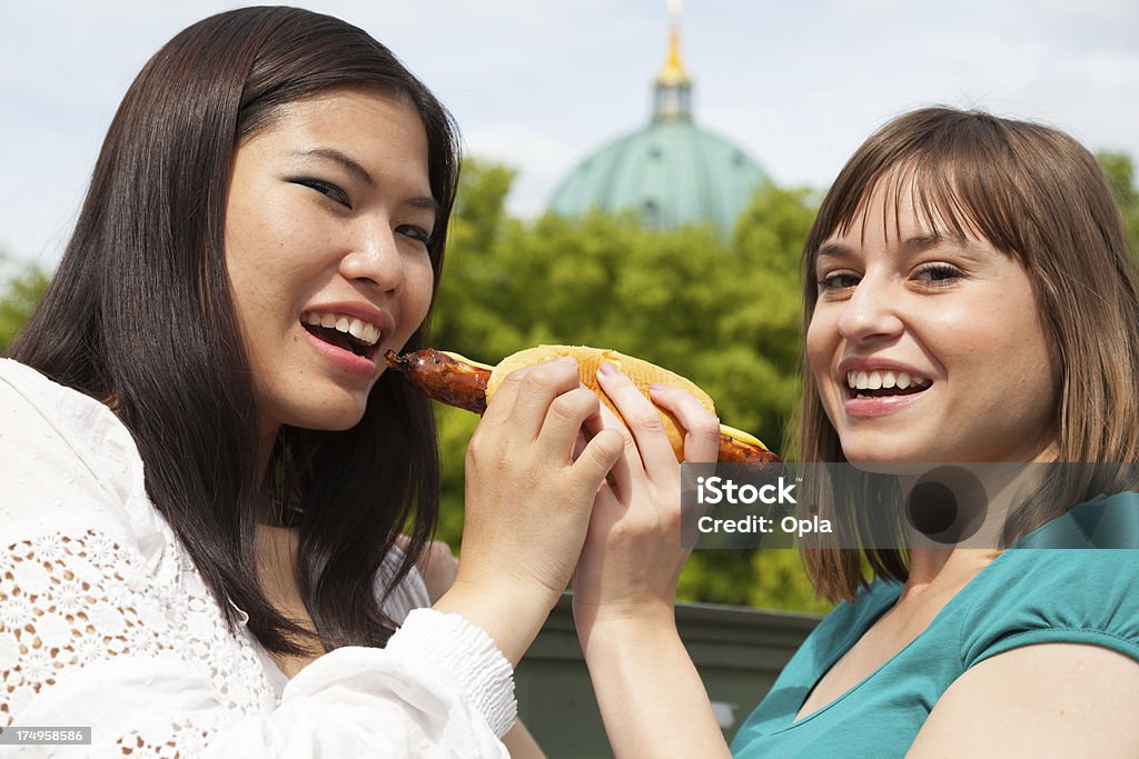 Two young women sharing a sausage roll 20-24 Years Stock Photo