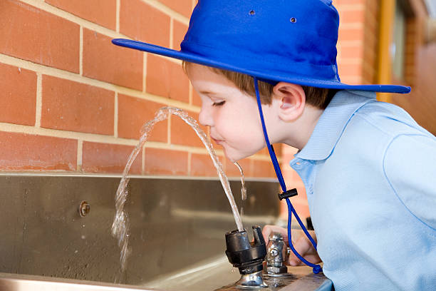 A five year old Australian school boy drinking from a water fountain.