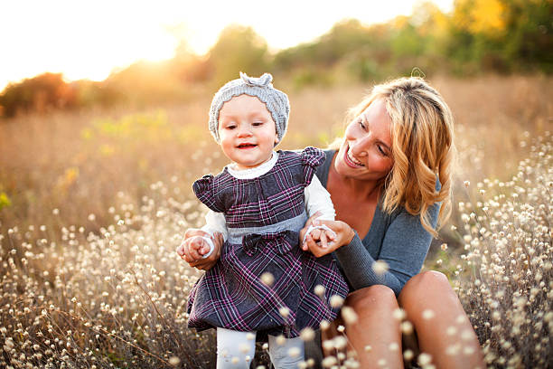 maman bébé fille souriant détient prenant premiers pas - baby first steps autumn child photos et images de collection