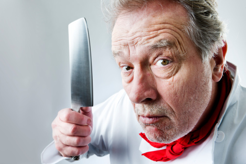 Portrait of a angry chef in your face threatening you with a knife.