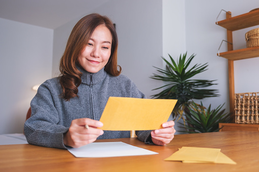 Portrait image of a young woman writing on a letter and envelopes