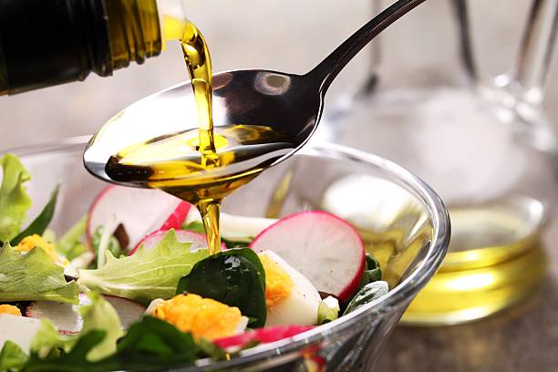 การเพิ่มน้ําสลัดลงในสลัดในชามแก้ว - salad oil ภาพสต็อก ภาพถ่ายและรูปภาพปลอดค่าลิขสิทธิ์