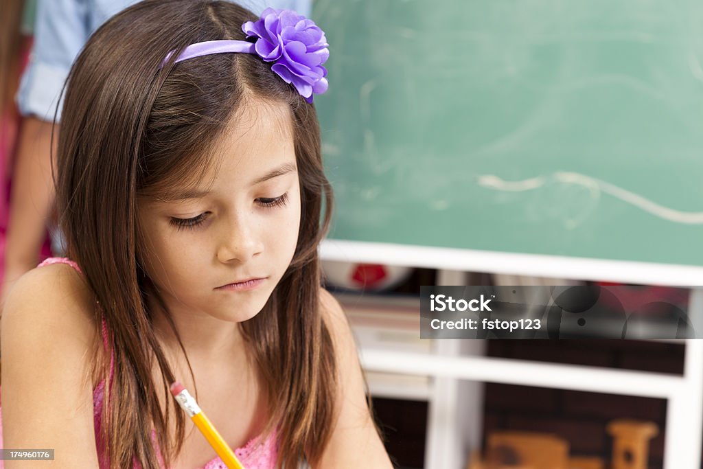小学生の女の子で、スクール形式でデスクを備えております。黒板とスチューデント背景。 - 1人のロイヤリティフリーストックフォト