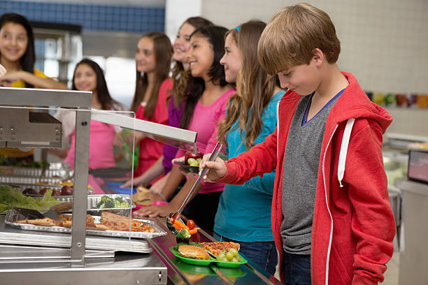 middle school students choosing healthy food in cafeteria lunch line - schoollunch stockfoto's en -beelden