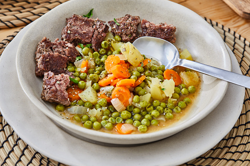 beef stew with vegetables in black pot on dark wooden background, selective focus