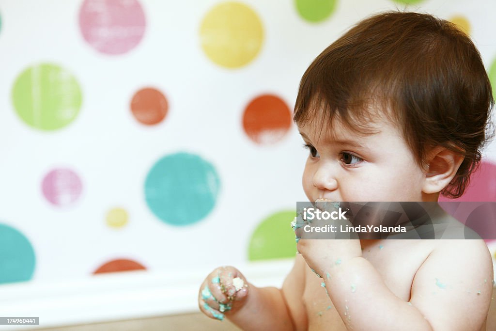 Baby Boy Eating First Birthday Cake "A portrait of a baby boy, sticky with icing, eating his first birthday cake. Festive polka dots in background. Some copy space." Birthday Stock Photo