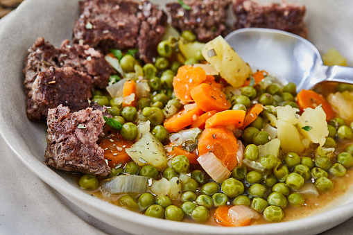 Green peas and beef meat, a healthy protein lunch after the workout, made of beef meat, green peas, potatoes, carrot and garlic, served in a modern plate on a rustic wooden home or restaurant table, representing a wellbeing and a healthy lifestyle, an image with a copy space