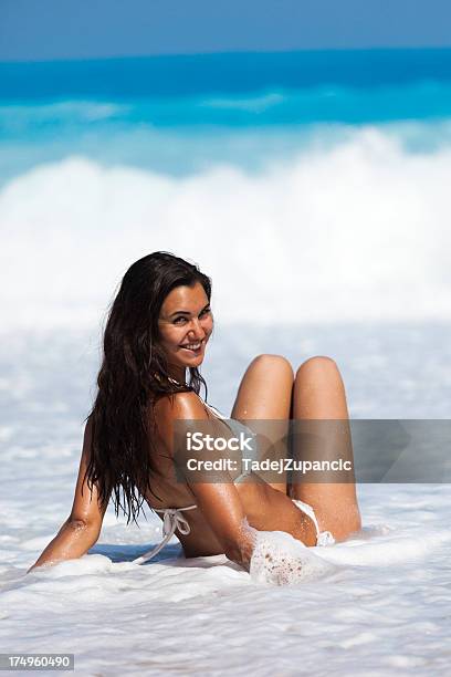 Foto de Jovem Mulher Sentada Na Praia e mais fotos de stock de Adulto - Adulto, Beleza, Céu Claro