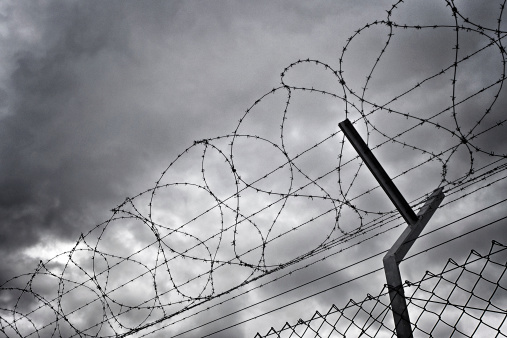 Barbed wire fence against a dramatic sky. Grain added to increase the dramatic effect.