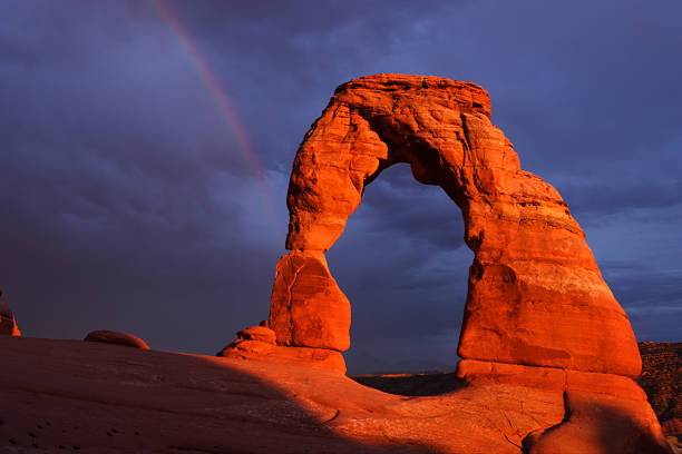 Delicate Arch in the Arches National Park on a morning, with snow mountain in the background and people hiking, like a heaven