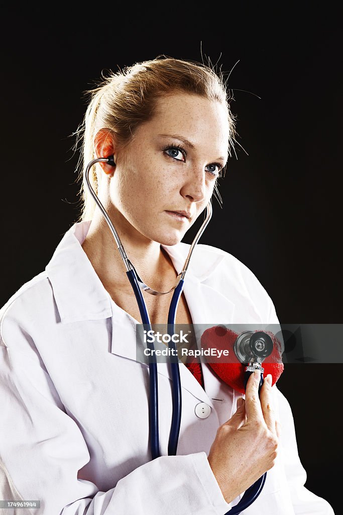 Красивая, но серьезные Молодой врач проверяет ее сердце, день Святого Валентина - Стоковые фото 20-29 лет роялти-фри